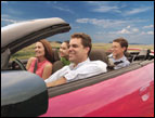 family riding in a red convertible on a road trip